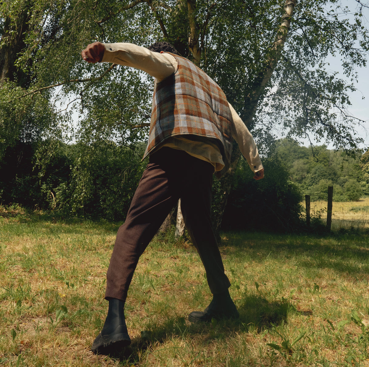 homme dans un camps portant une veste sans manches et un pantalon marron