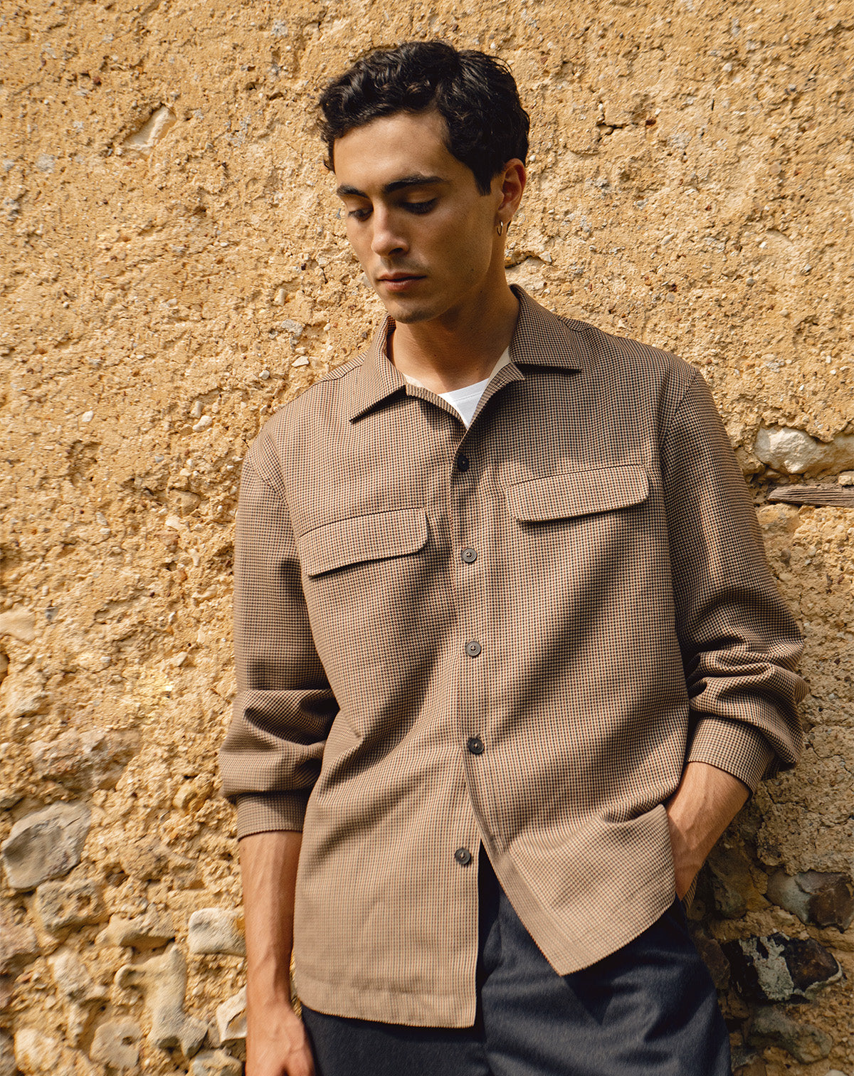 homme adossée à un mur portant une chemise à motifs