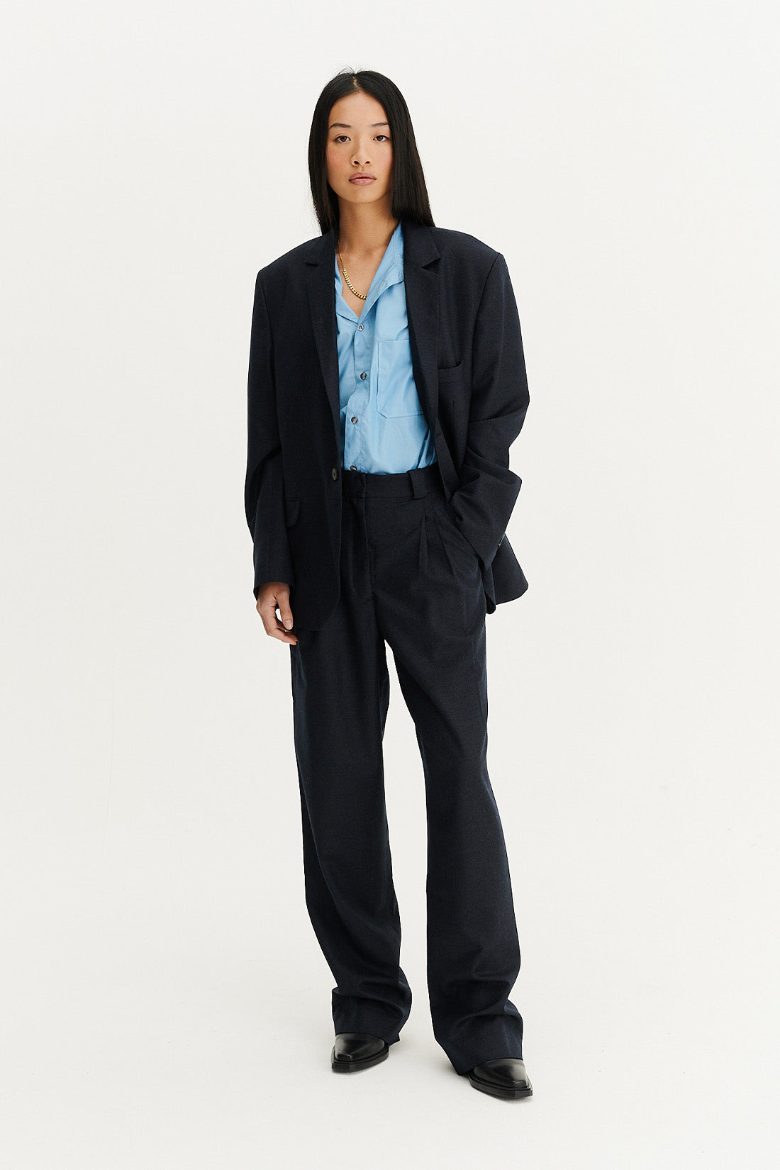 femme en ensemble de tailoring bleu marine dans un studio photo