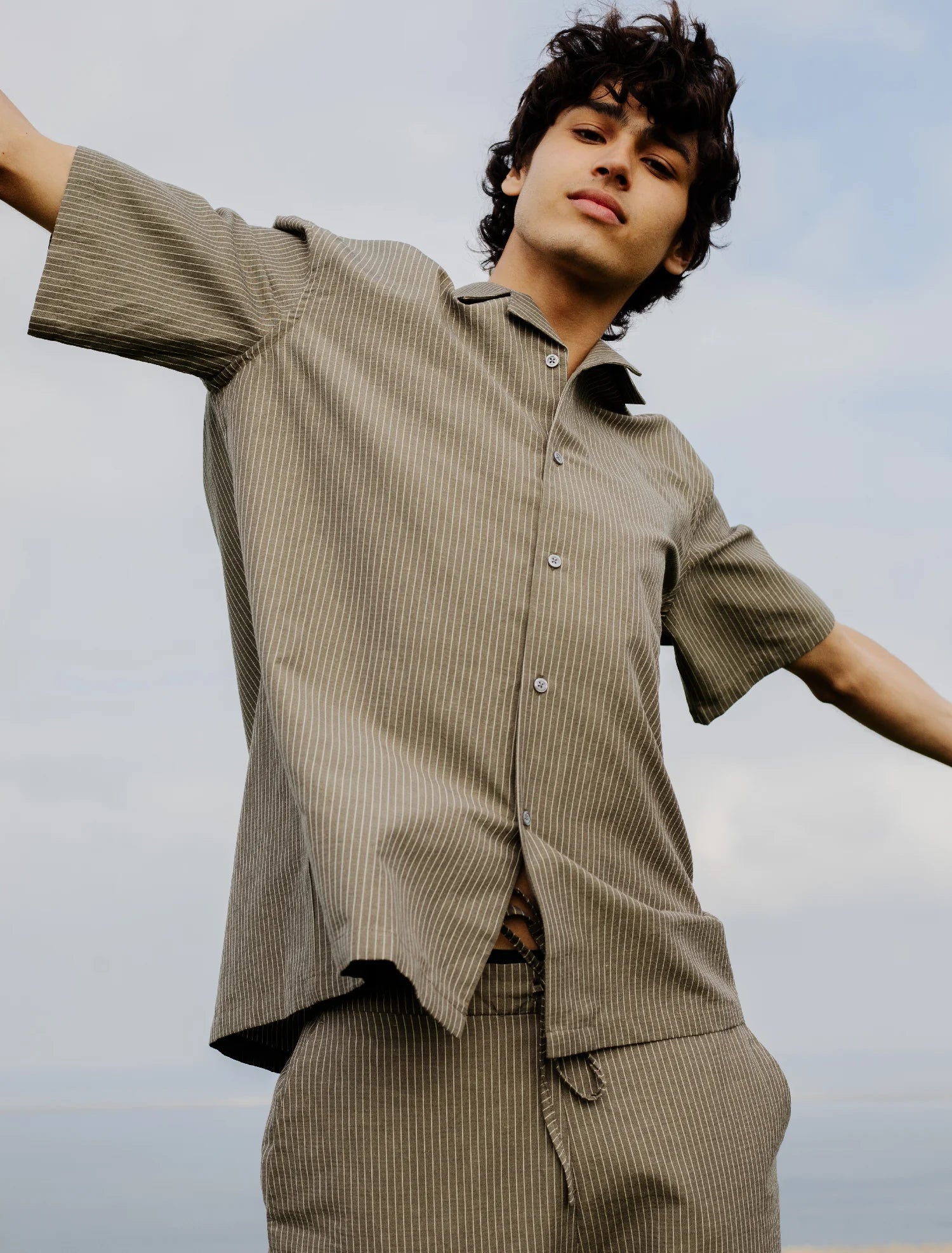 chemise grise à rayures blanches portée par un homme les bras en l'air