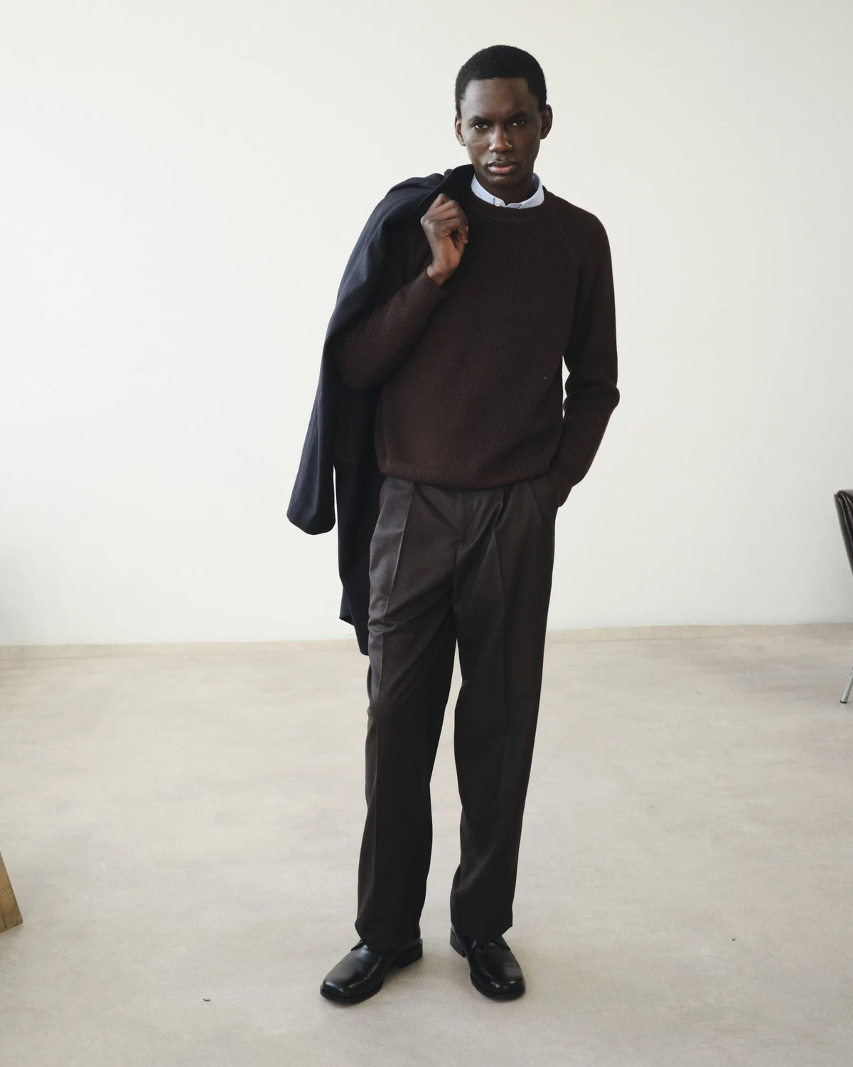 Silhouette homme en maille brune et manteau bleu porté sur l'épaule