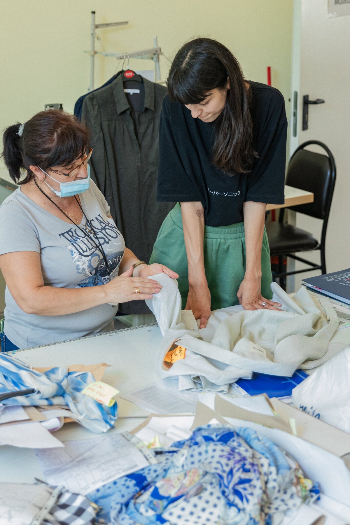 Deux professionnelles examinent un vêtement sur une table dans un atelier de confection en Roumanie.